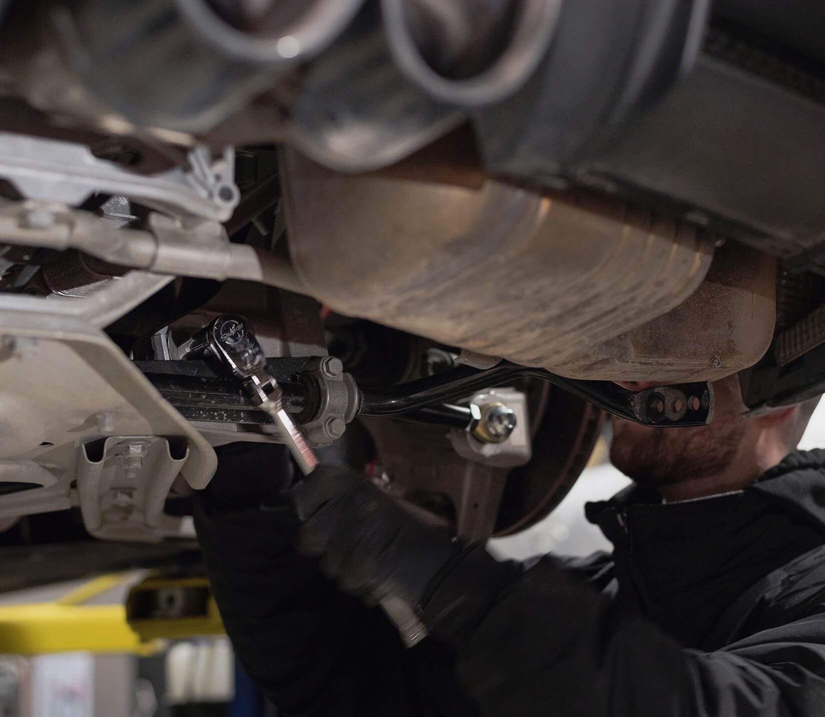 mechanic working underneath a lifted car