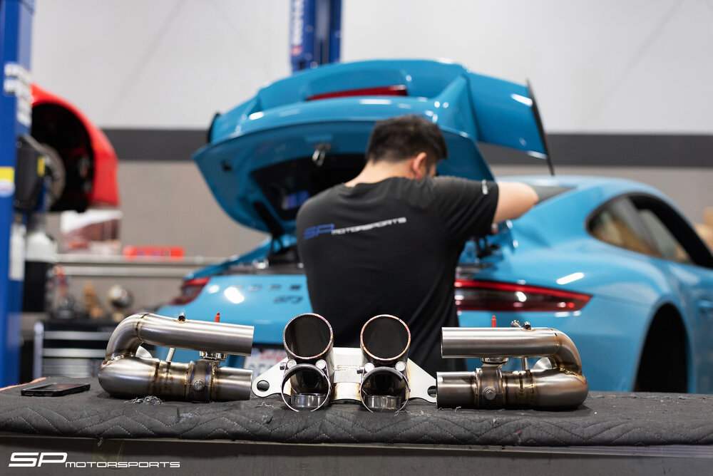 Bolt On Exhaust Solutions – We offer a variety of ultra high end bolt on exhaust systems for your Porsche & other exotic cars. Systems such as:-Soul Performance-SPM Grand Am Exhaust-Dundon Motorsport-Cargraphic-Akrapovich Titanium& More… mechanic working on exhaust