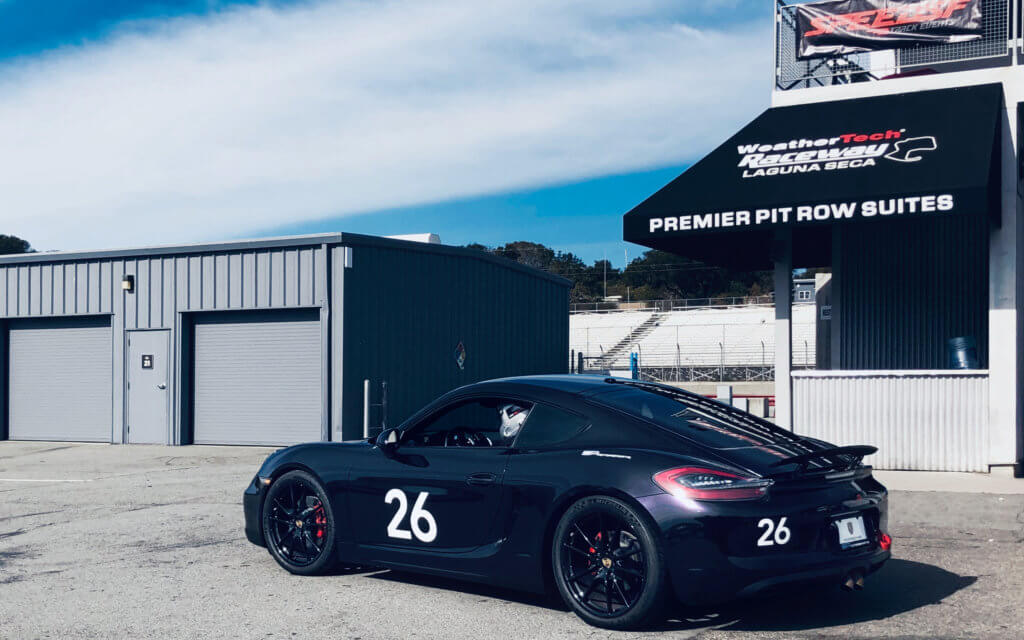 #26 Purple Cayman S Sits in front of the laguna seca sign by the garages